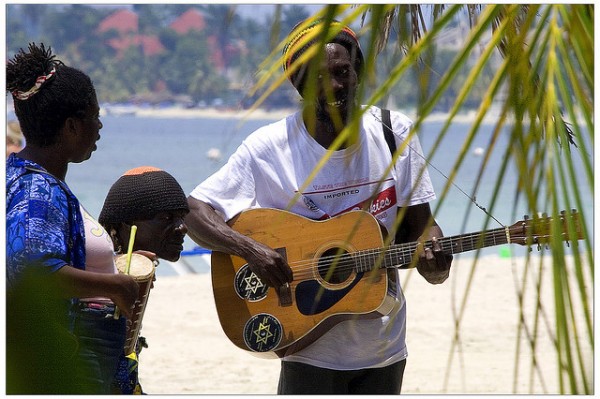 man strumming his guitar on the beach in jamaica