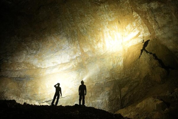 Team members inside Cheve Cave look on at a massive borehole inside the cave. (National Geographic/Kasia Biernacka)